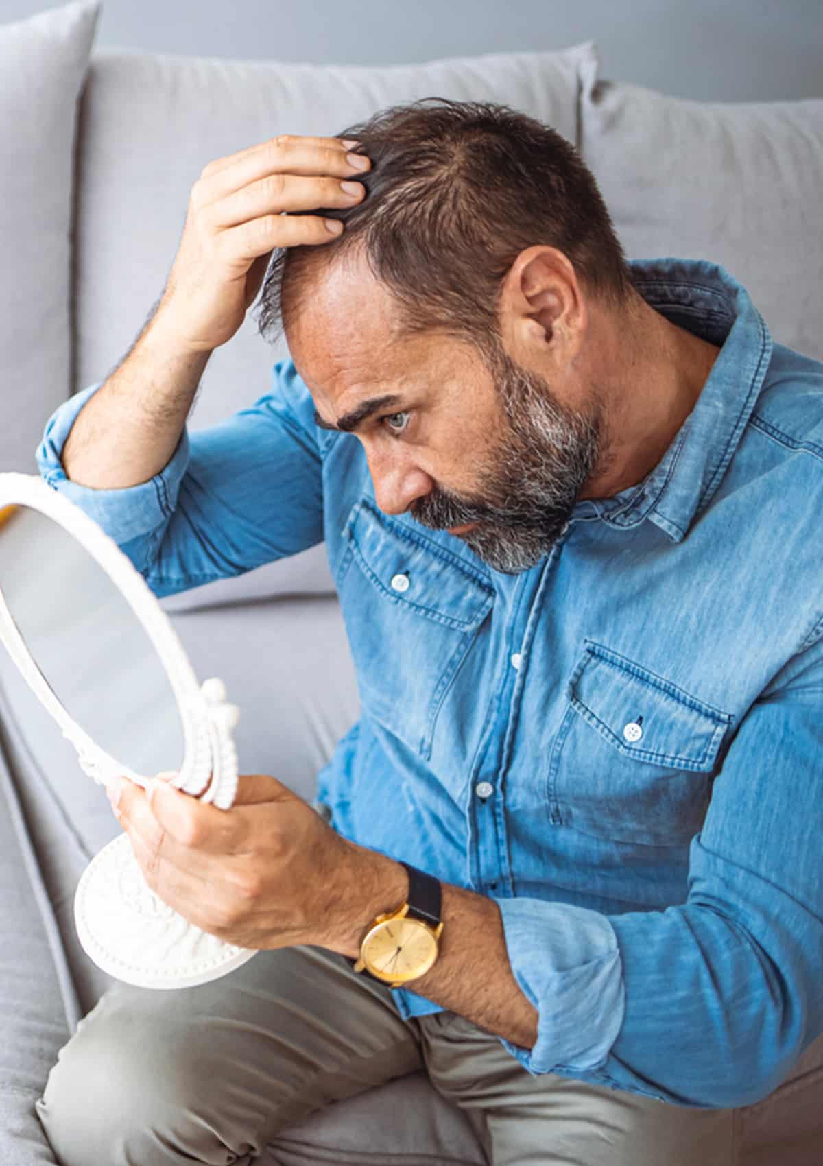 a man looking at his hair in the mirror